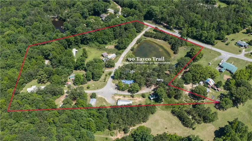 An aerial perspective showcases a large, verdant lot featuring a private pond and ample space for development.
