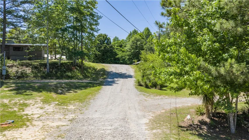 A long gravel driveway leads to a secluded wooded retreat.