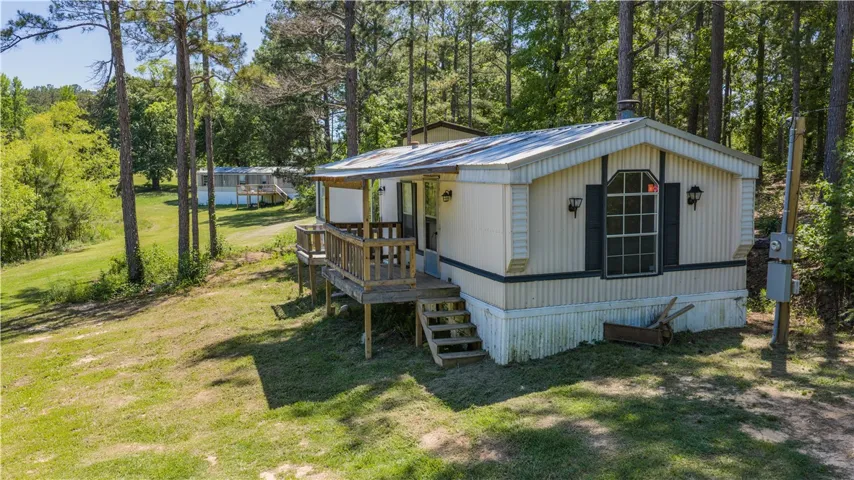 A manufactured home nestled among a lush, treed landscape.