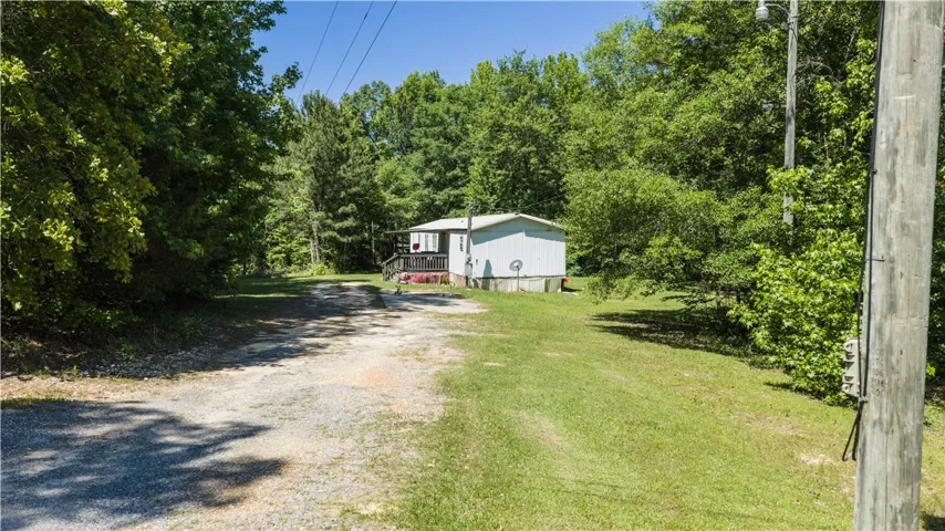 A private driveway leads to a modest dwelling, nestled among a lush, verdant treeline.