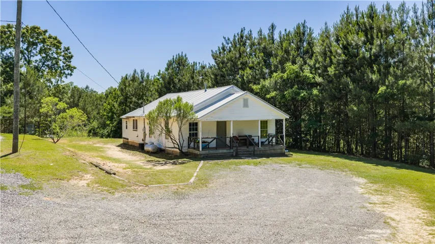 A charming country retreat with a welcoming front porch and ample gravel parking.