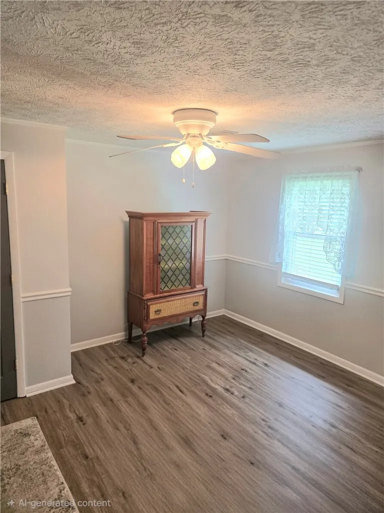 A well-lit room showcasing rich flooring and a convenient ceiling fan.