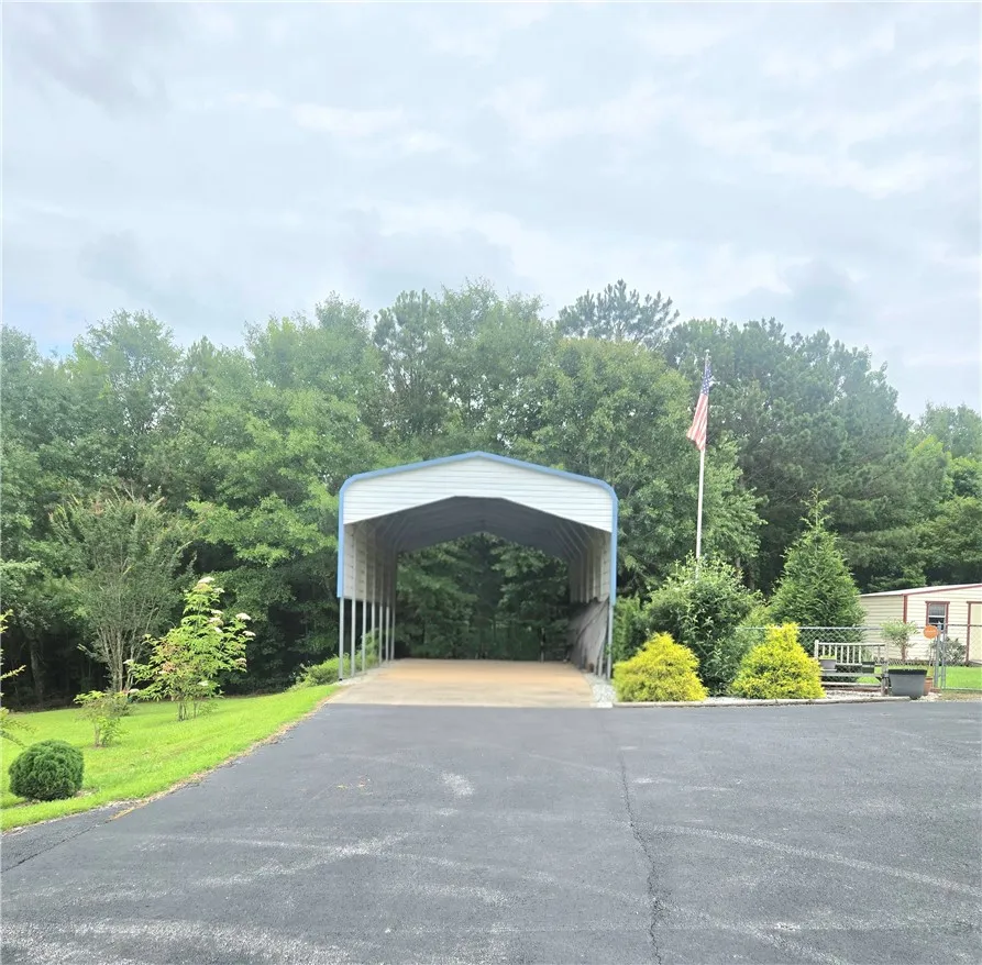 Drive into this property featuring a detached carport and a paved driveway.