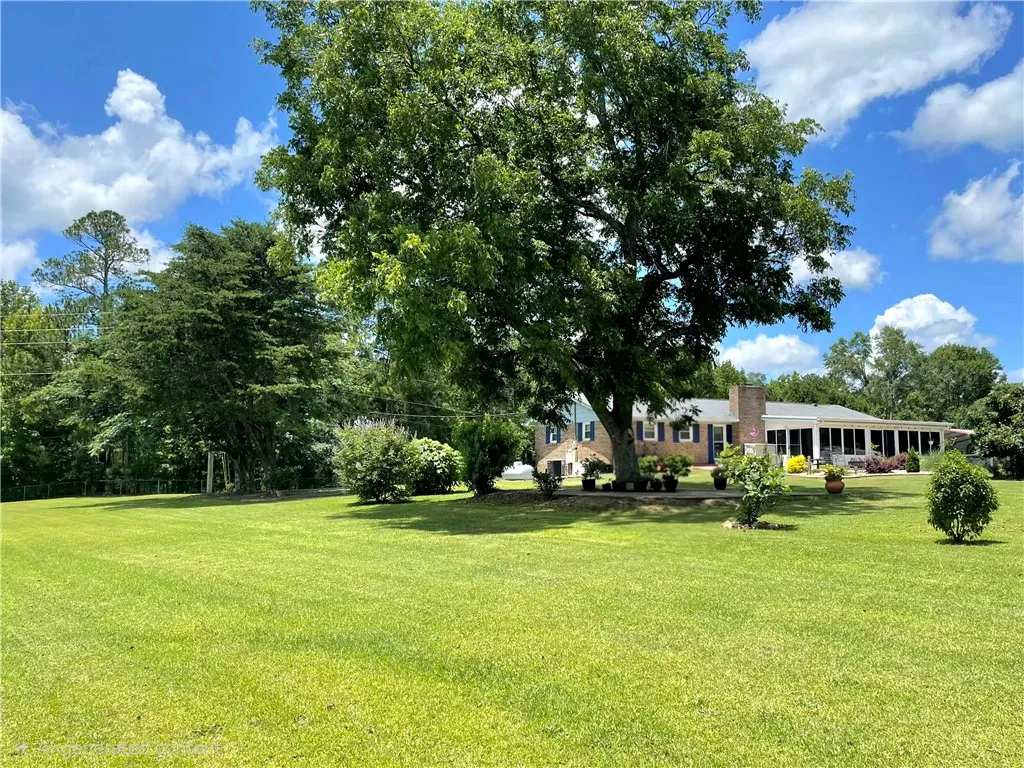 Vast green lawn and mature trees frame this charming residence, perfect for tranquil living.