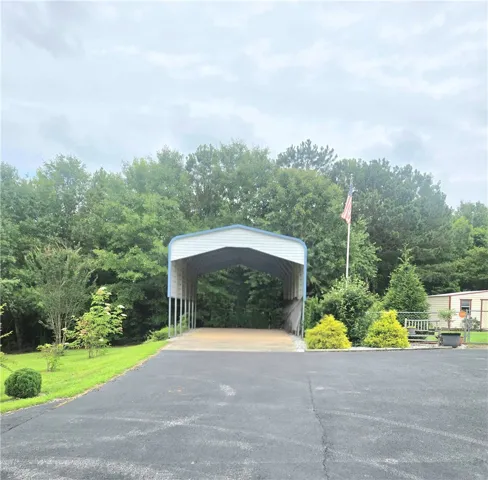 Drive into this property featuring a detached carport and a paved driveway.