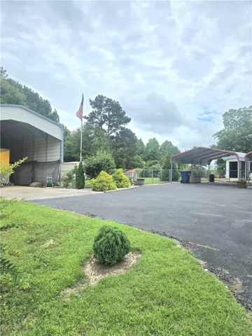 An asphalt driveway leads to covered storage and parking options, offering practical utility.