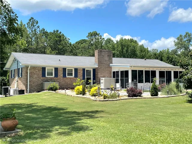 A classic brick exterior blends with an inviting sunroom, surrounded by lush, maintained grounds.