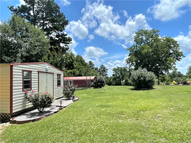 A spacious yard awaits, complete with a functional shed and mature shade trees.