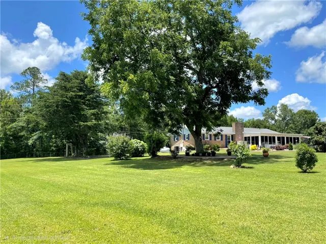Vast green lawn and mature trees frame this charming residence, perfect for tranquil living.