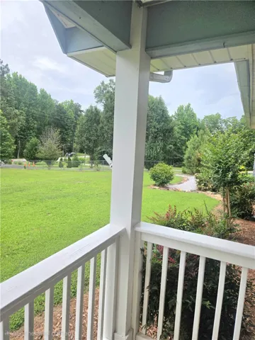 Relax on the inviting porch overlooking a spacious yard and lush green landscaping.