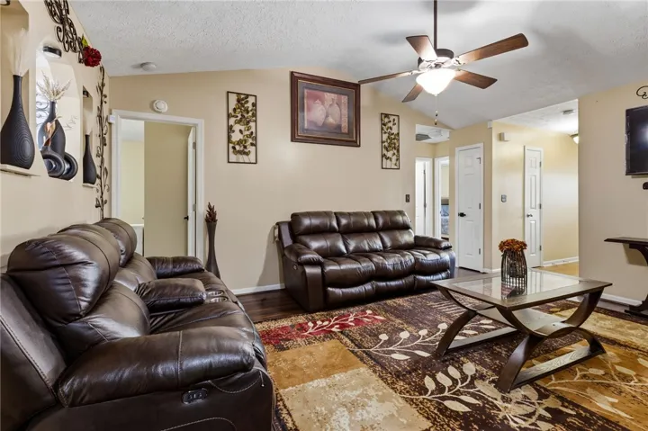Relax in this comfortable living room featuring rich wood flooring and a classic ceiling fan.