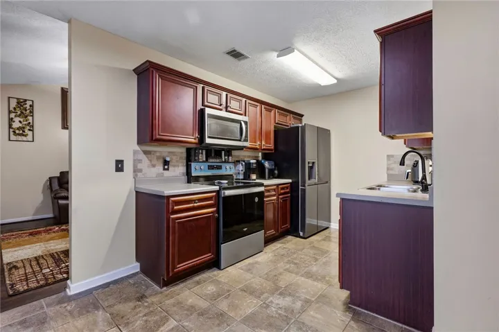 A compact kitchen boasts rich wood cabinetry, stainless steel appliances, and practical tile flooring.