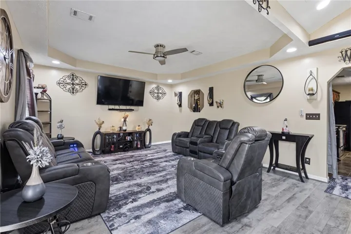 Recessed lighting illuminates this well-appointed living room featuring a tray ceiling and wood flooring.
