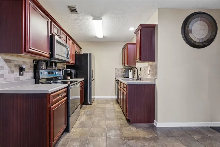 A well-appointed kitchen features rich cabinetry, modern appliances, and a durable tile floor.