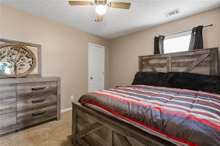 Well-appointed bedroom featuring a warm color palette, plush carpeting, and a rustic wooden bed frame.