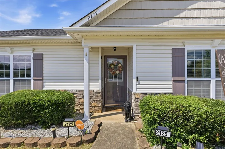 A welcoming stone and siding facade with a neat shrub border creates appealing curb appeal.