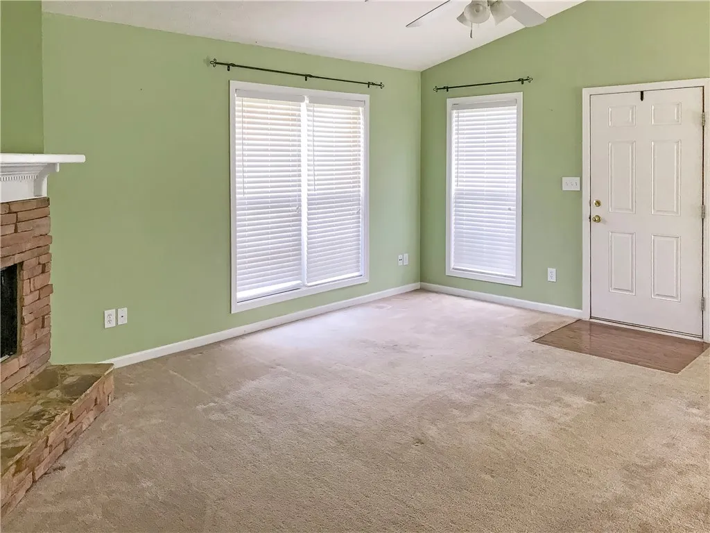 A cozy living space features a charming brick fireplace and inviting carpeting.
