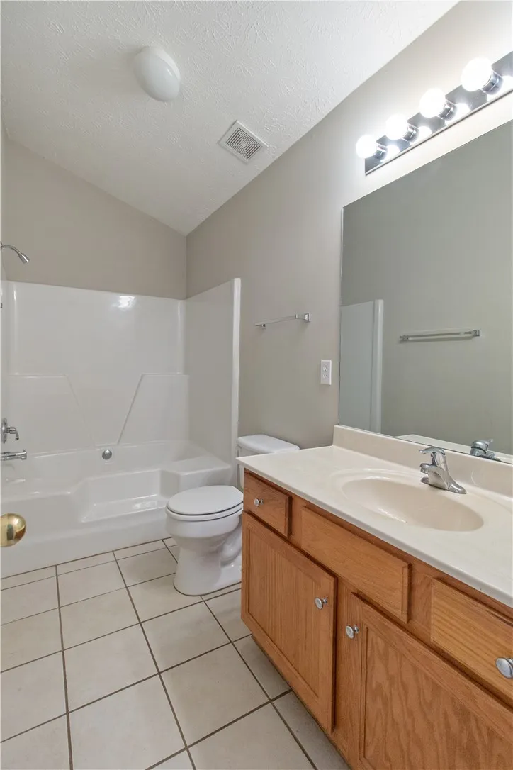 A well-lit bathroom provides a functional vanity and a combined shower-tub unit for daily routines.