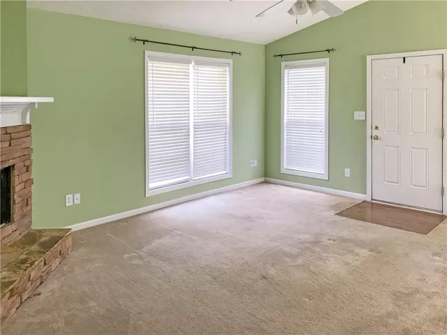 A cozy living space features a charming brick fireplace and inviting carpeting.
