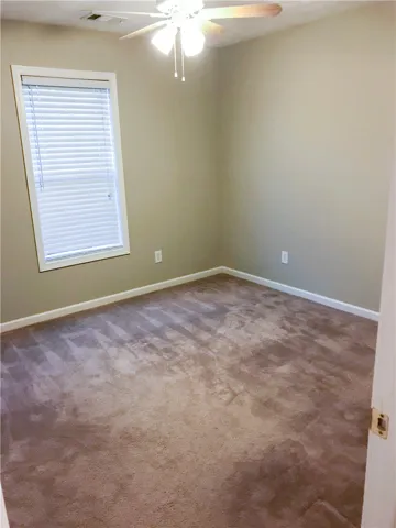 A versatile room featuring carpeted floors and a cooling ceiling fan, ready for personal touches.