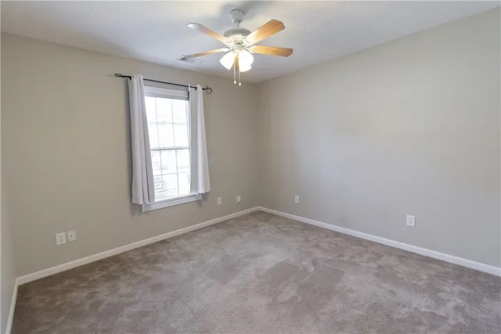 A well-proportioned bedroom with a light-toned carpet and a window for natural illumination.