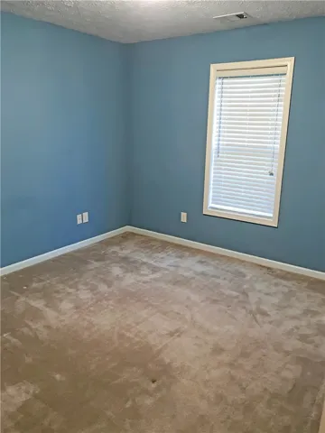 An inviting room awaits with neutral carpet and a window for natural light.