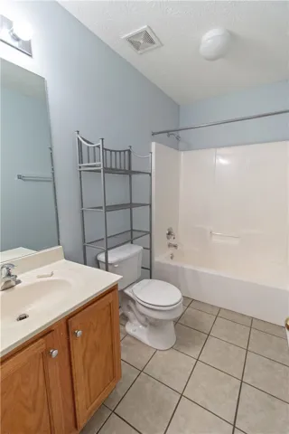 Functional full bathroom featuring a tub and shower combination with a single vanity and tile flooring.