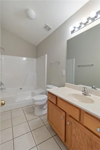 A well-lit bathroom provides a functional vanity and a combined shower-tub unit for daily routines.
