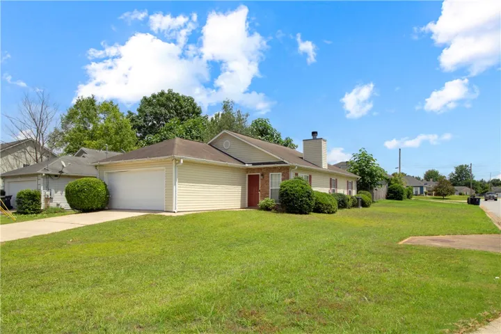 A classic ranch home, clad in warm beige siding, is nestled amidst a generous green lawn and mature landscaping.