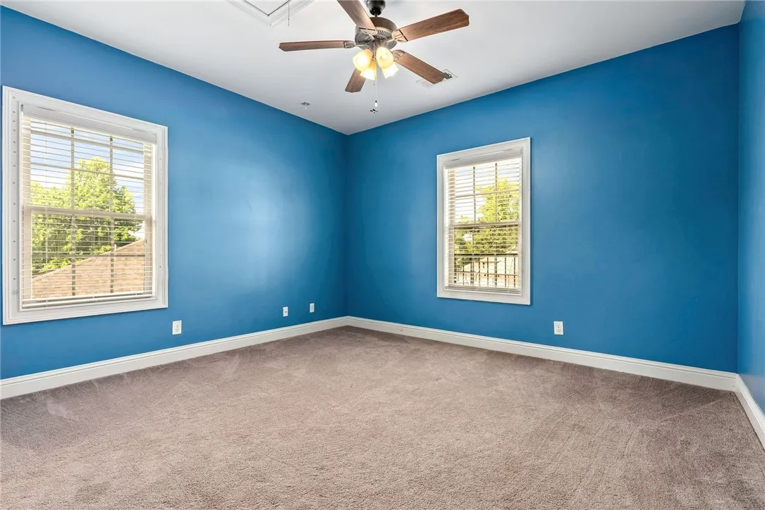 Comfortable bedroom with carpeted floors and two well-lit windows.