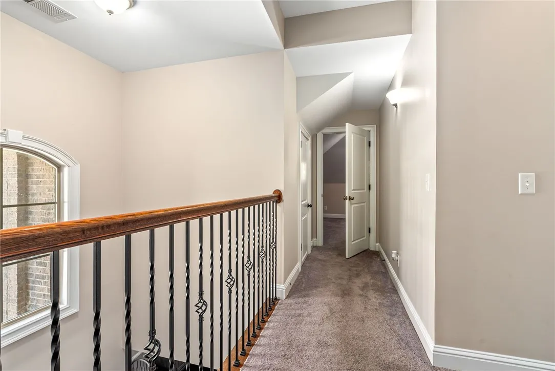 A graceful staircase with wrought iron balusters leads to an upper-level hallway.