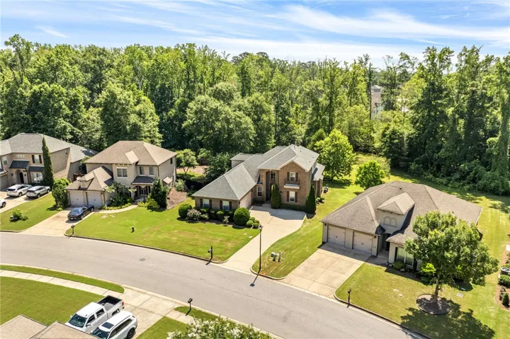 An aerial perspective reveals a tree-lined neighborhood, showcasing suburban homes with attached garages and manicured lawns.