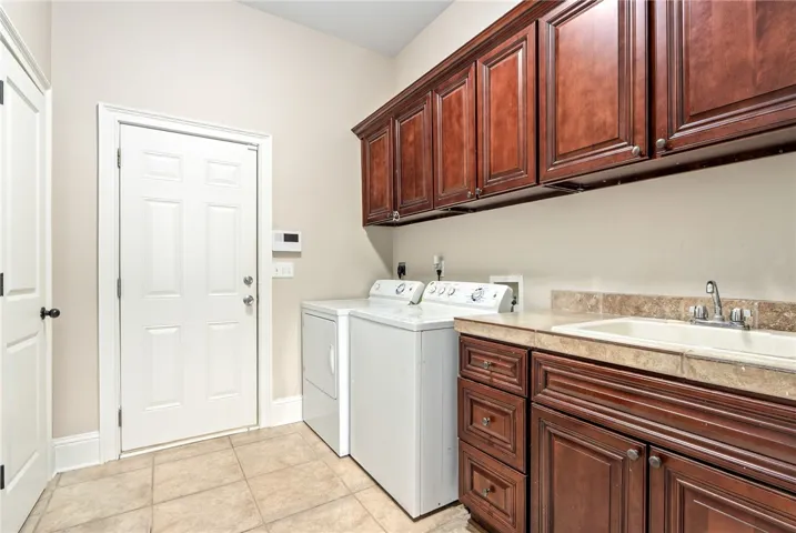 Ample storage cabinetry and practical laundry sink define this functional utility space.