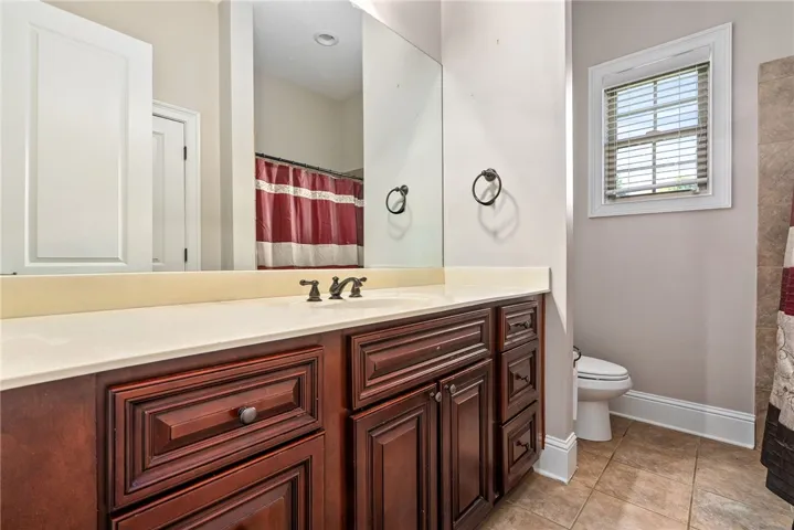 A refined bathroom featuring a spacious vanity with rich wood cabinetry and ample counter space.