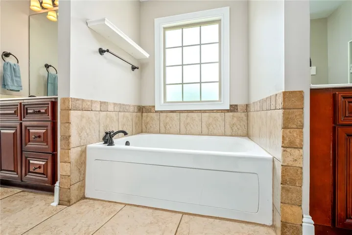 Indulge in relaxation with this inviting soaking tub, perfectly positioned under a well-lit window, featuring attractive tile surrounds.