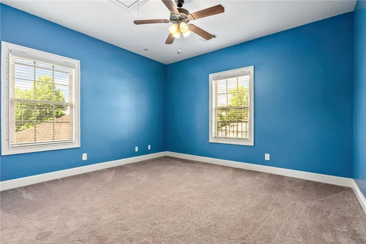 Comfortable bedroom with carpeted floors and two well-lit windows.