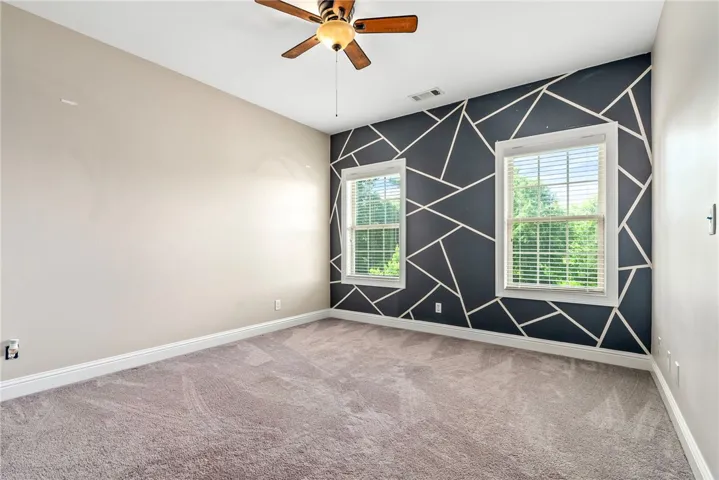 Two windows naturally illuminate this spacious bedroom with a unique geometric accent wall.