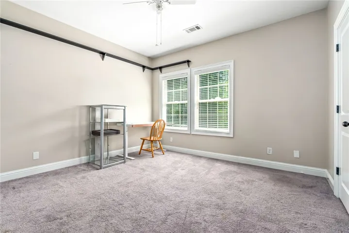 Well-lit room, perfect for a home office, features dual windows overlooking the landscape.