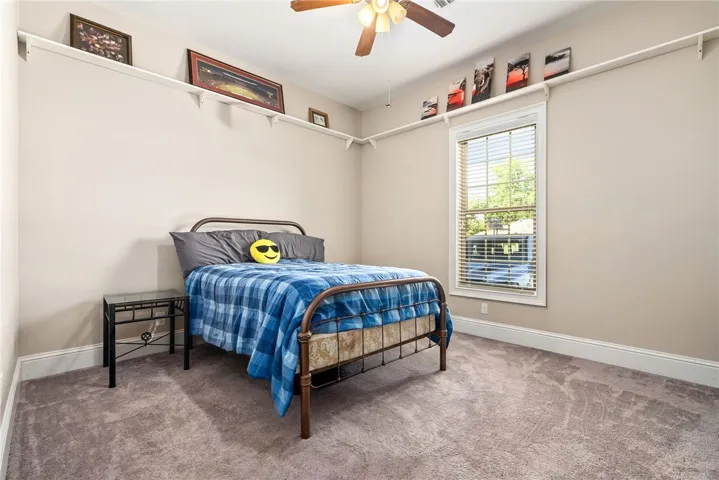 A comfortable bedroom features plush carpeting and a large window for ample natural light.