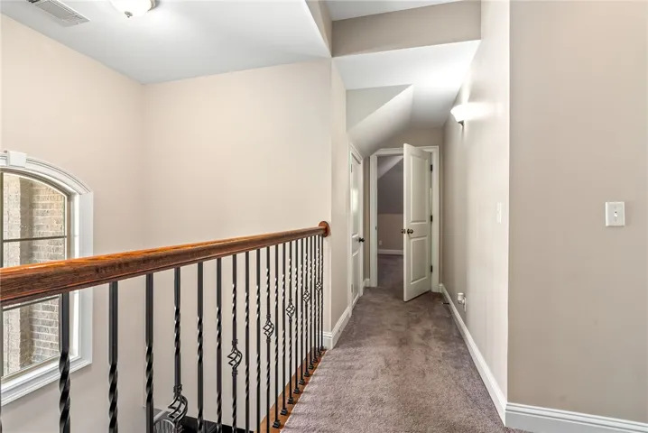A graceful staircase with wrought iron balusters leads to an upper-level hallway.