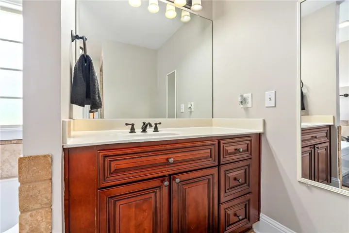 A rich wood vanity with a pristine white countertop and modern fixtures offers ample storage.