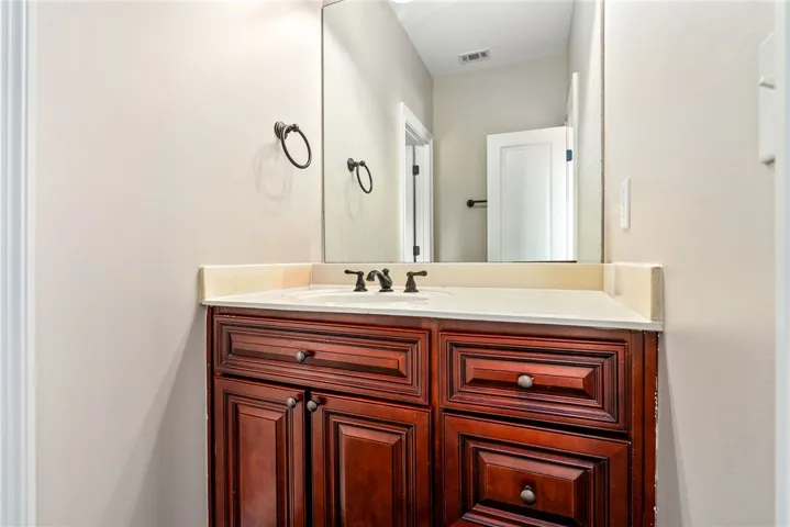 A dark wood vanity with a white countertop and large mirror creates a tidy bathroom space.