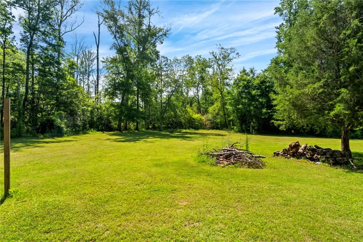A verdant, open field extends to a lush tree line under a brilliant sky, offering a private setting.