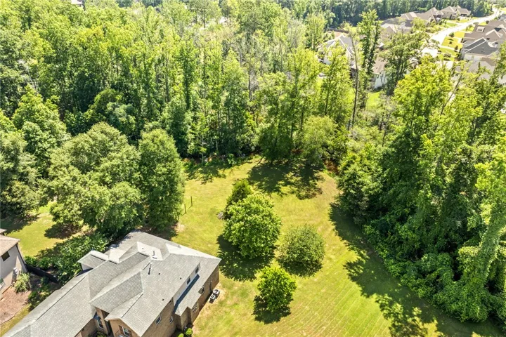 A verdant, tree-lined backyard offers privacy and ample green space for outdoor enjoyment.