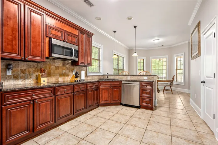 A well-appointed kitchen features rich cabinetry, stainless appliances, and a convenient breakfast bar.