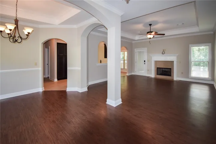 Rich hardwood floors flow through an open layout with elegant archways and a cozy fireplace.