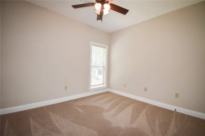 A well-lit bedroom with comfortable carpeting and a convenient ceiling fan for ultimate comfort.