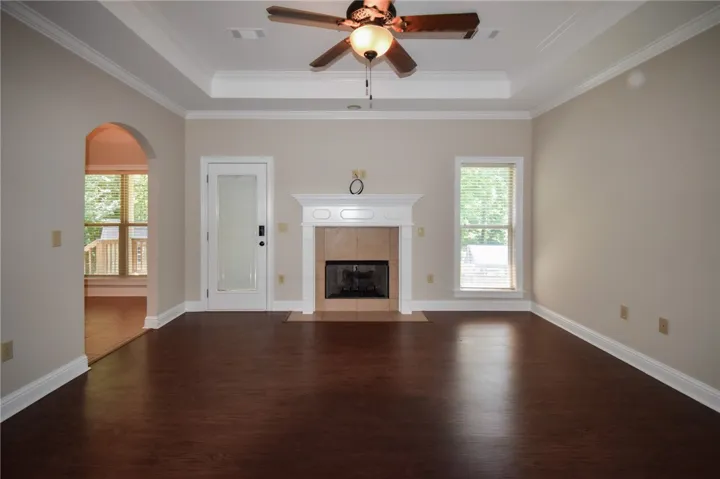 Rich hardwood flooring leads to a cozy fireplace with a tiled hearth and a decorative mantel.