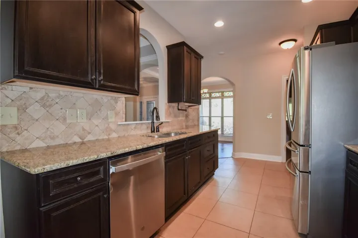 Elegant kitchen featuring granite countertops and dark wood cabinetry with stainless steel appliances.