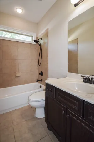 A well-appointed bath features a tiled tub and shower, alongside a dark wood vanity with a pristine white countertop.